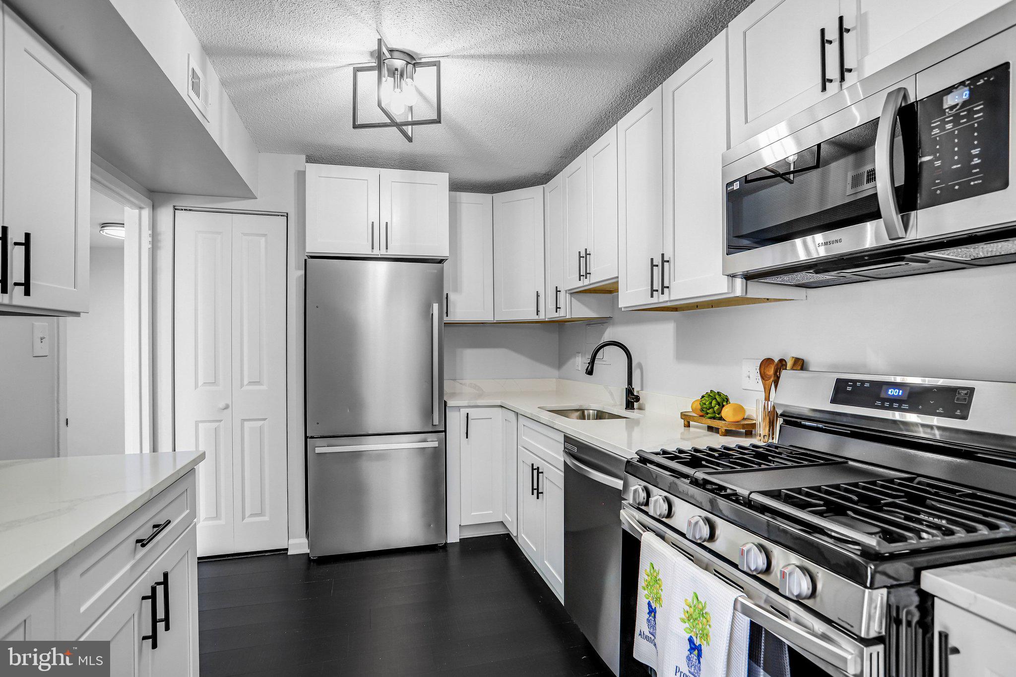 1836 Metzerott Road, Unit 627 Adelphi, MD 20783 - Photo 9 of 27 a kitchen with stainless steel appliances granite countertop a refrigerator a stove a sink dishwasher and white cabinets with wooden floor