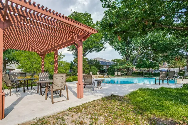 a view of a swimming pool with chairs and table in the patio