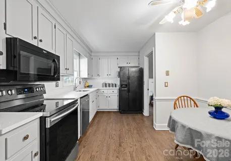 a kitchen with stainless steel appliances a stove a sink dishwasher a refrigerator and a microwave oven with wooden floor