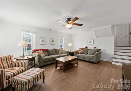 a living room with furniture a ceiling fan a lamp and a window