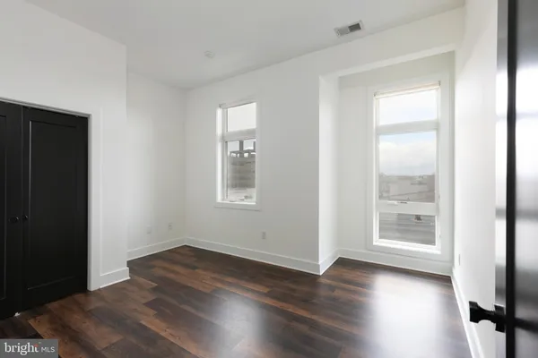 an empty room with wooden floor and windows