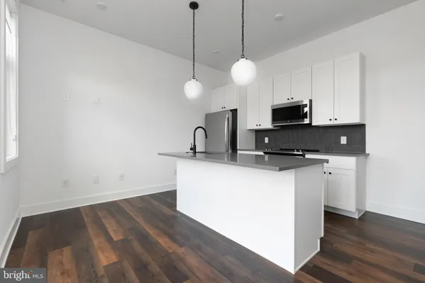 a kitchen with microwave a stove and wooden floor