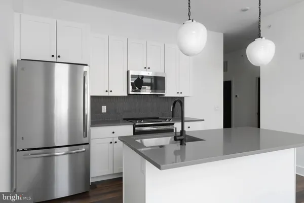 a kitchen with stainless steel appliances granite countertop a refrigerator a stove a sink and a chandelier