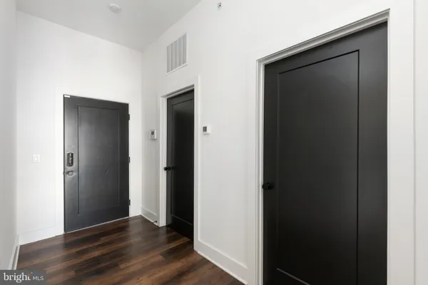 a view of an empty room with wooden floor and closet