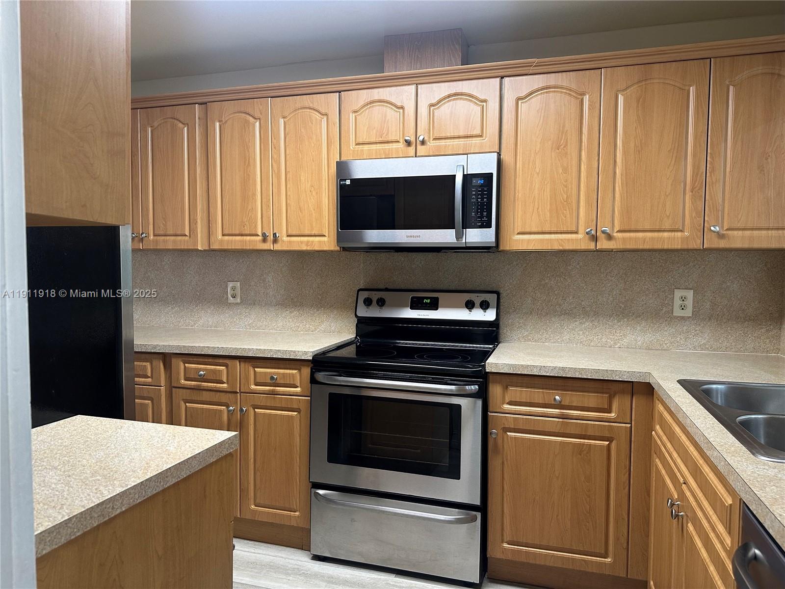 11354 Southwest 87th Terrace, Unit 11354 Miami, FL 33173 - Photo 18 of 25 a kitchen with stainless steel appliances granite countertop a stove microwave and cabinets