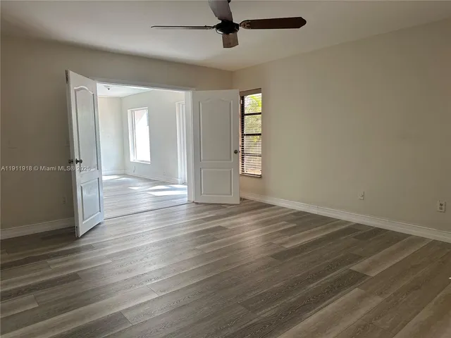 an empty room with wooden floor cabinet and windows