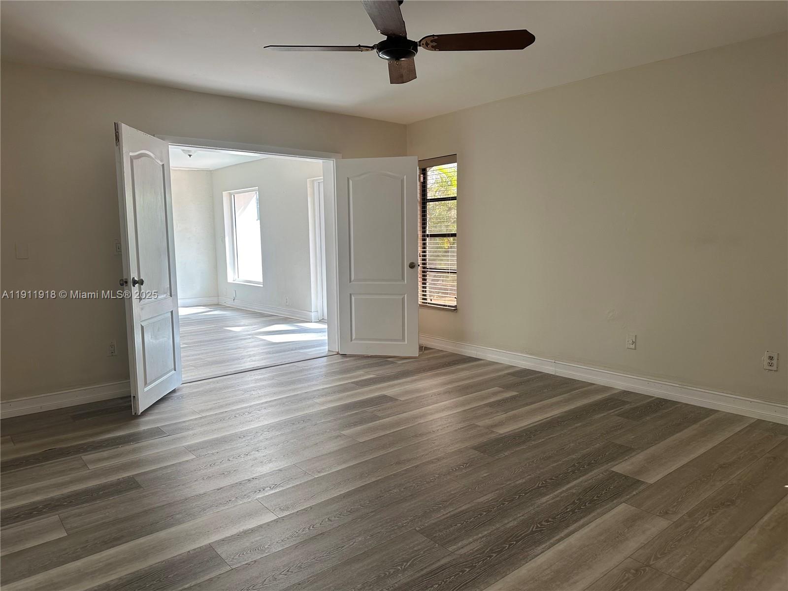 11354 Southwest 87th Terrace, Unit 11354 Miami, FL 33173 - Photo 7 of 25 an empty room with wooden floor cabinet and windows