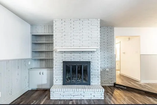 a view of an empty room with wooden floor and a fireplace