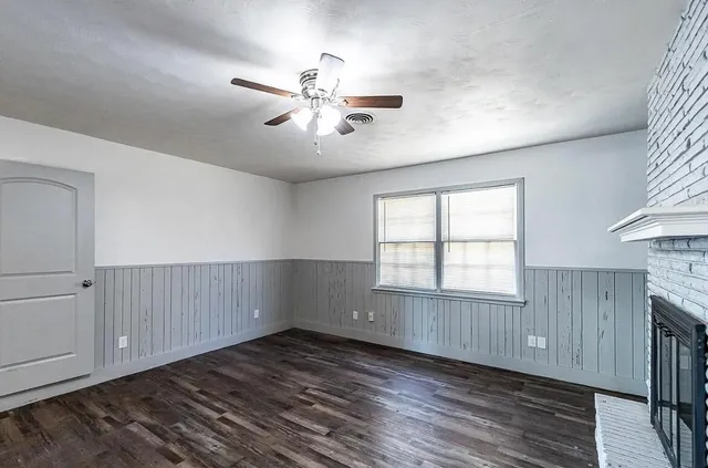 a view of an empty room with a window and wooden floor