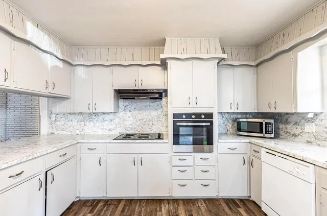 a kitchen with granite countertop white cabinets white stainless steel appliances and a sink