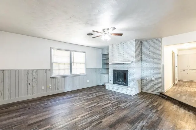 an empty room with windows and fireplace