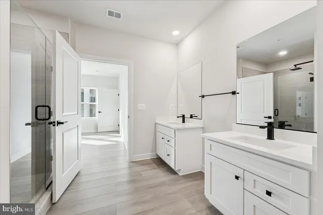 a spacious bathroom with a double vanity sink a mirror and a shower