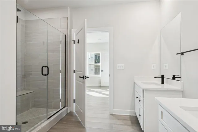 a large white bathroom with a double vanity sink a mirror and a shower