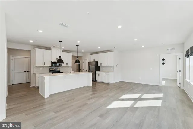 a living room with furniture and kitchen view with wooden floor