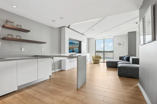 a living room with granite countertop couches a coffee table and kitchen view with wooden floor