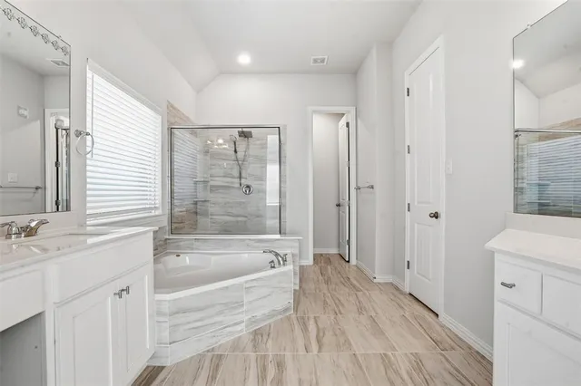 a spacious bathroom with a tub sink shower and a mirror