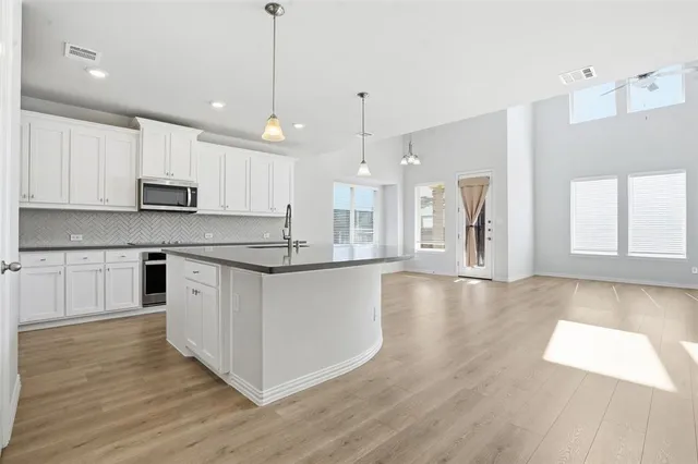a large kitchen with cabinets wooden floor and a window