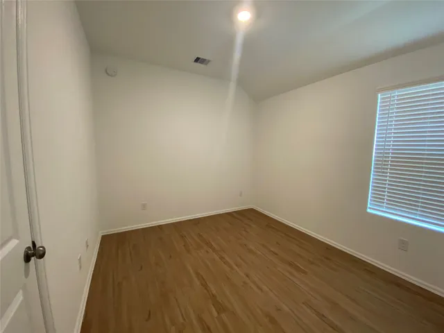 a view of a room with wooden floor and a window