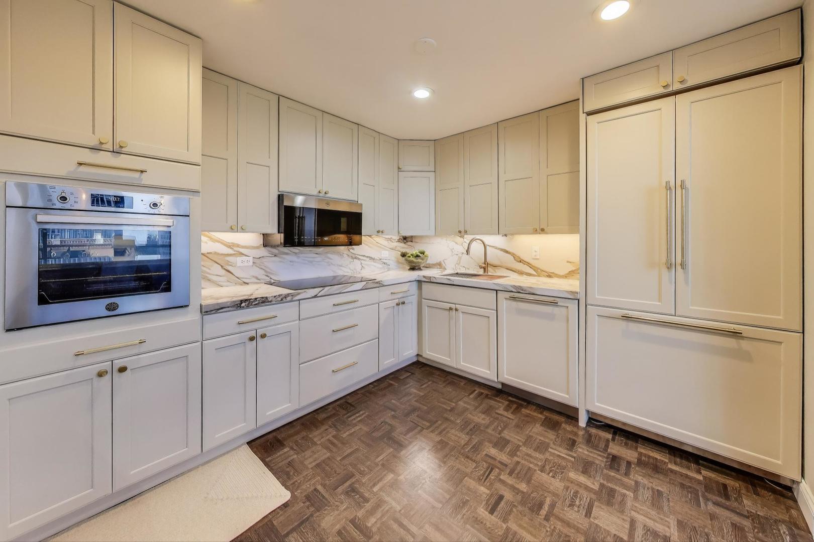 201 East Chestnut Street, Unit 24C Chicago, IL 60611 - Photo 7 of 33 a kitchen with granite countertop white cabinets and white appliances