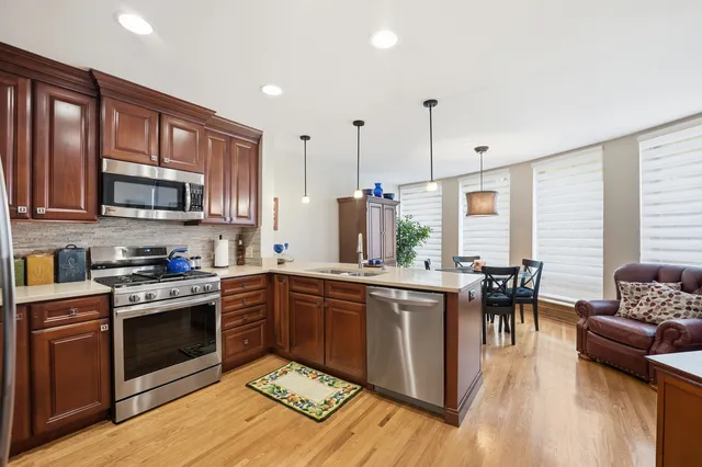 a kitchen with stainless steel appliances granite countertop wooden floors a stove and a microwave