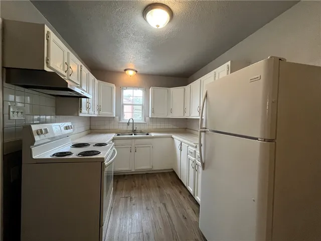 a kitchen with a refrigerator a sink dishwasher and a stove top oven