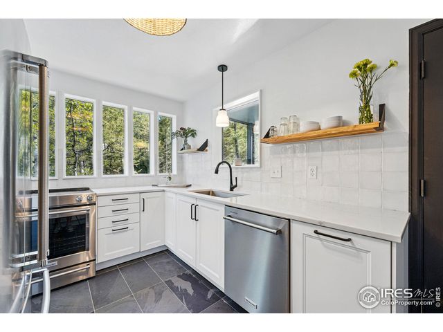 a kitchen with stainless steel appliances granite countertop a sink a stove and a window