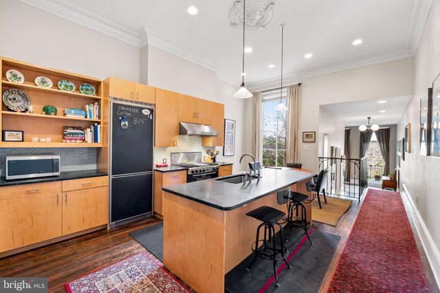 a dining room with stainless steel appliances kitchen island granite countertop a table chairs and a refrigerator