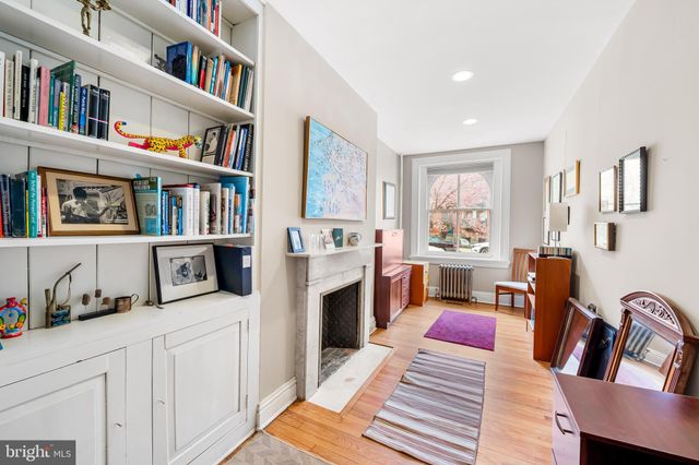 a living room with stainless steel appliances furniture a fireplace and a flat screen tv