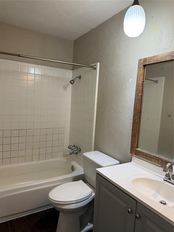 3801 Guthrie Road Garland, TX 75043 - Photo 10 of 24 White subway tile shower surround with a built-in tub, wood-finish mirror frame, and a vanity with a white countertop and integrated sink