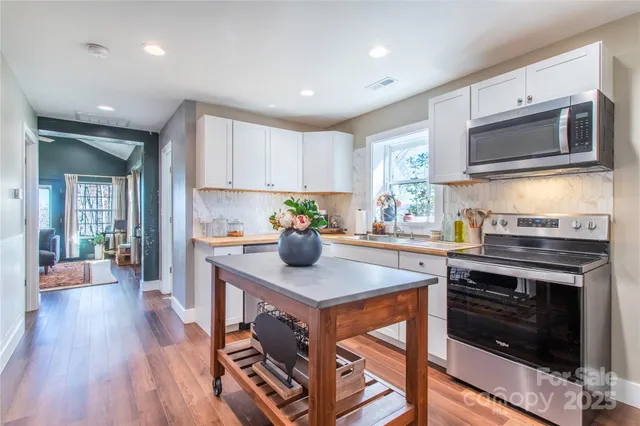 a kitchen with stainless steel appliances kitchen island granite countertop a stove a sink and a microwave