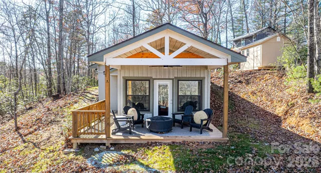 a view of house with yard outdoor seating and covered with trees
