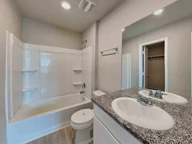 a bathroom with a granite countertop sink toilet mirror and bathtub