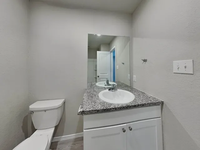 a bathroom with a granite countertop toilet sink and mirror