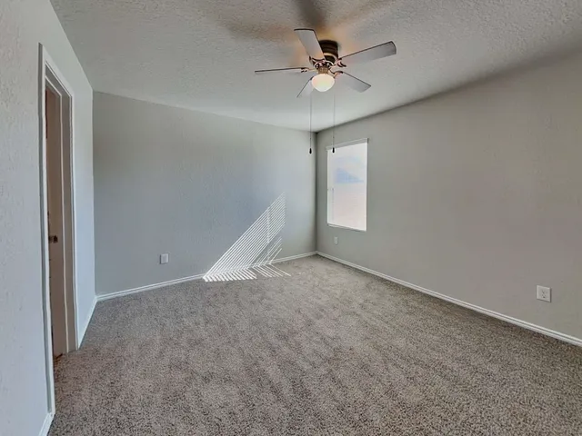 an empty room with a chandelier fan and windows