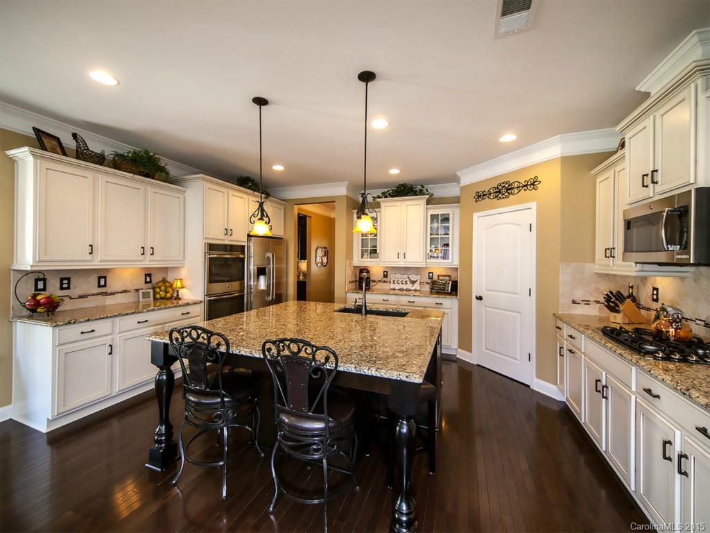 930 Solandra Way Tega Cay, SC 29708 - Photo 8 of 24 a kitchen with stainless steel appliances kitchen island granite countertop a stove a refrigerator a kitchen island a dining table and chairs with wooden floor