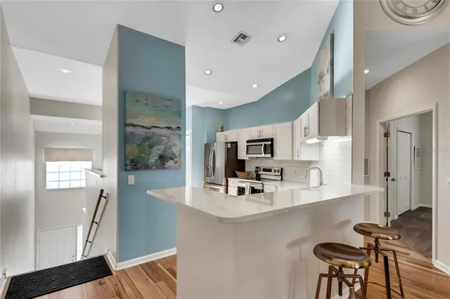 a kitchen with stainless steel appliances a sink a stove a microwave a refrigerator a sink and cabinets