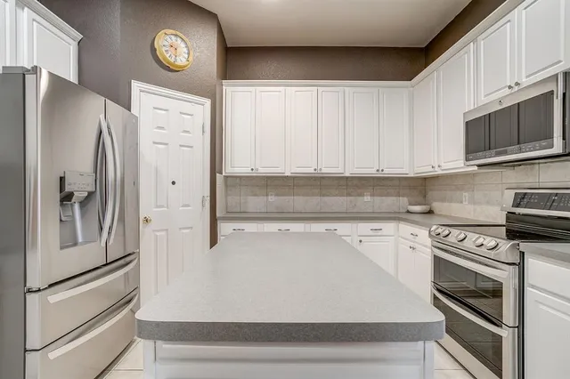 a kitchen with stainless steel appliances a refrigerator a stove and white cabinets