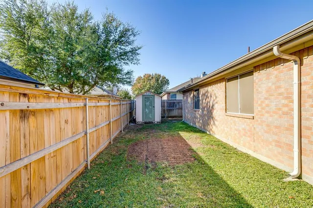 a view of a backyard with wooden fence and large trees