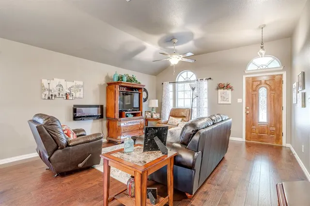 a living room with furniture a chandelier and a dining table with wooden floor