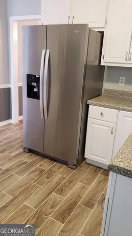 a view of a refrigerator in kitchen and an empty room