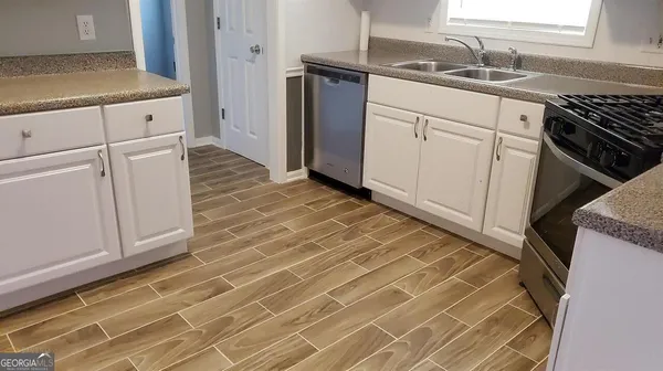 a kitchen with granite countertop a sink stove and cabinets