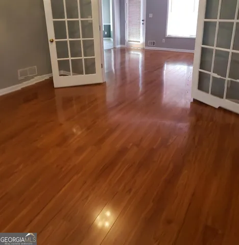 an empty room with wooden floor and windows