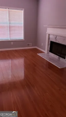 a view of empty room with wooden floor and fireplace