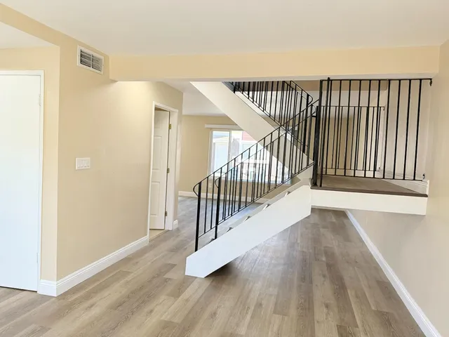 a view of a hallway with wooden floor and stairs