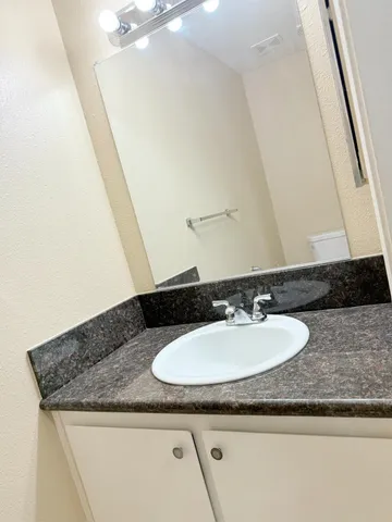 a bathroom with a granite countertop sink and a mirror