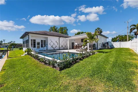 a view of a house with a big yard potted plants and a large tree