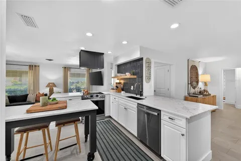 a kitchen with a stove a sink a kitchen island with a dining table and chairs