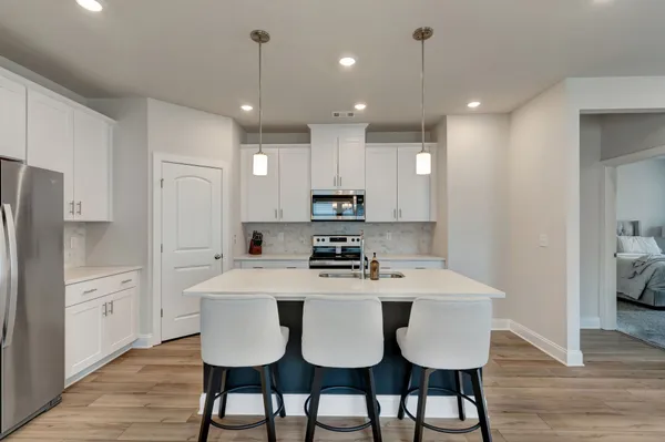 a kitchen with stainless steel appliances granite countertop a dining table chairs refrigerator and microwave