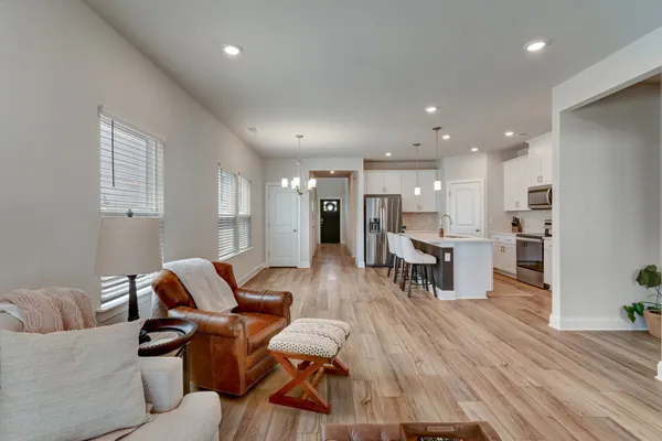 a living room with furniture and kitchen view with wooden floor