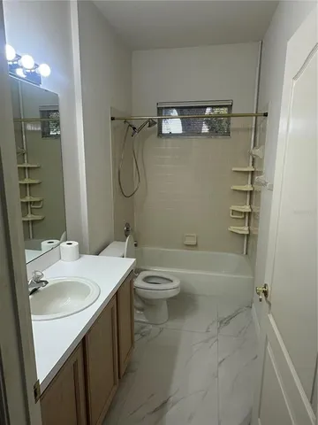 a bathroom with a granite countertop bathtub shower sink vanity and toilet